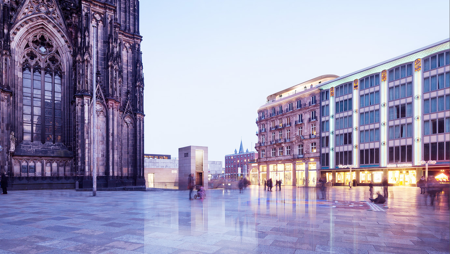 Abendlicher Blick auf den Kölner Dom und die Domplatte mit DomCarré und Dom Hotel im Hintergrund